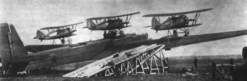 Un Tupolev TB-3 y tres Polikarpov I-5.Se ve la rampa para la carga de los aviones. La aeronave central fue izada en la parte superior del fuselaje a mano