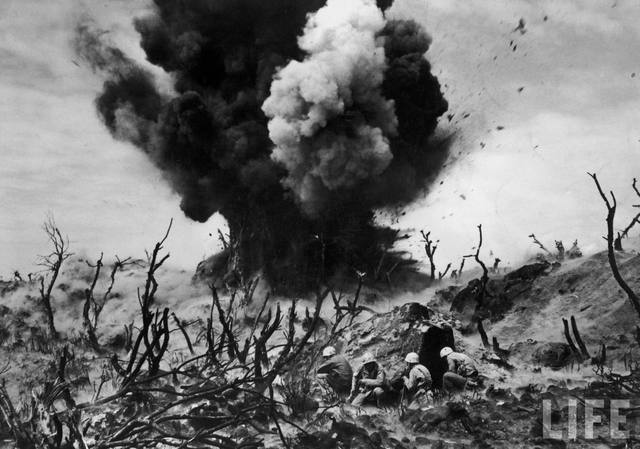 Marines estadounidenses se cubren mientras los explosivos destruyen una fortificación japonesa. Iwo Jima, 1945