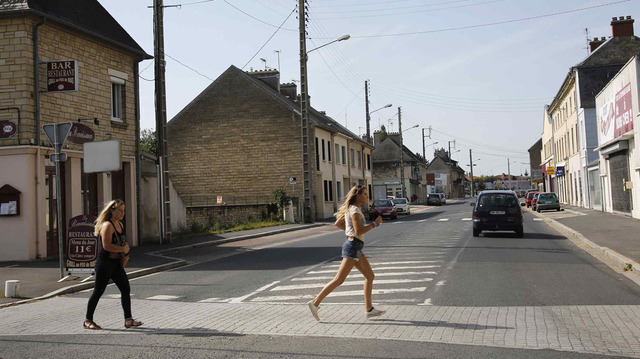 Unas niñas corren a través de la calle en el cruce de la calle Holgate y RN-13, en la ciudad normanda de Carentan