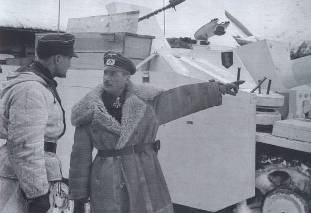 En la cabeza de puente de Narva, junto impartiendo órdenes a un oficial. Al fondo un StuG III con pintura de camuflaje invernal